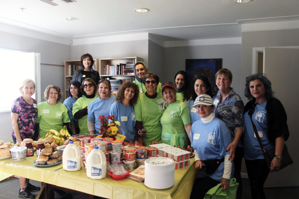 Image of a group of volunteers, smiling and standing around a table of food